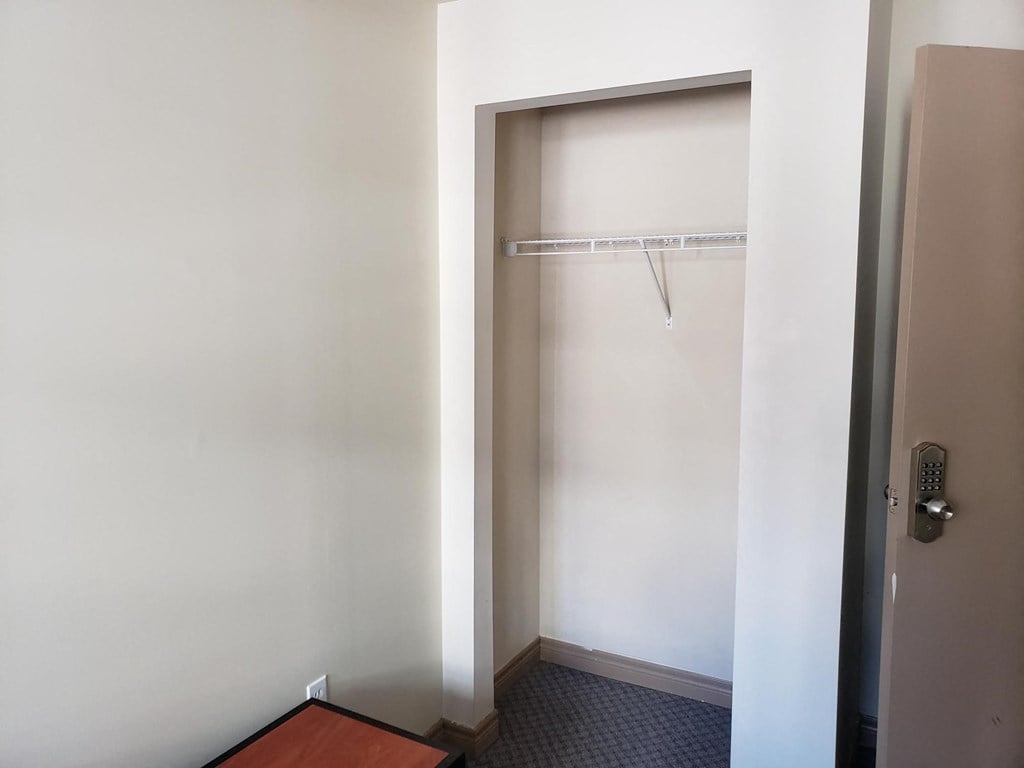 a small closet in a room with a door to a shower