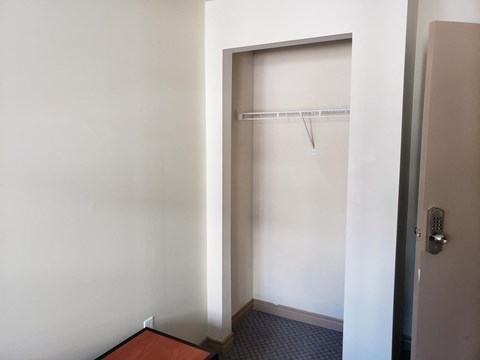 a small closet in a room with a door to a shower