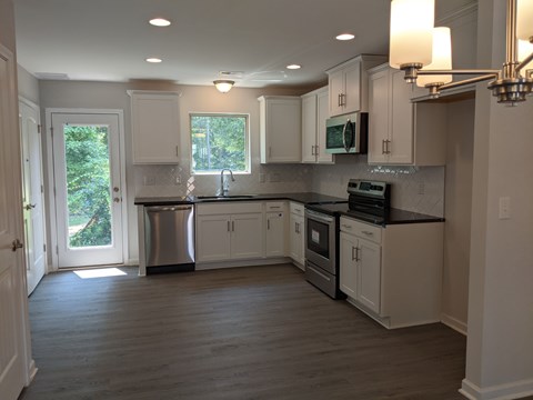 A kitchen with white cabinets and a black countertop.