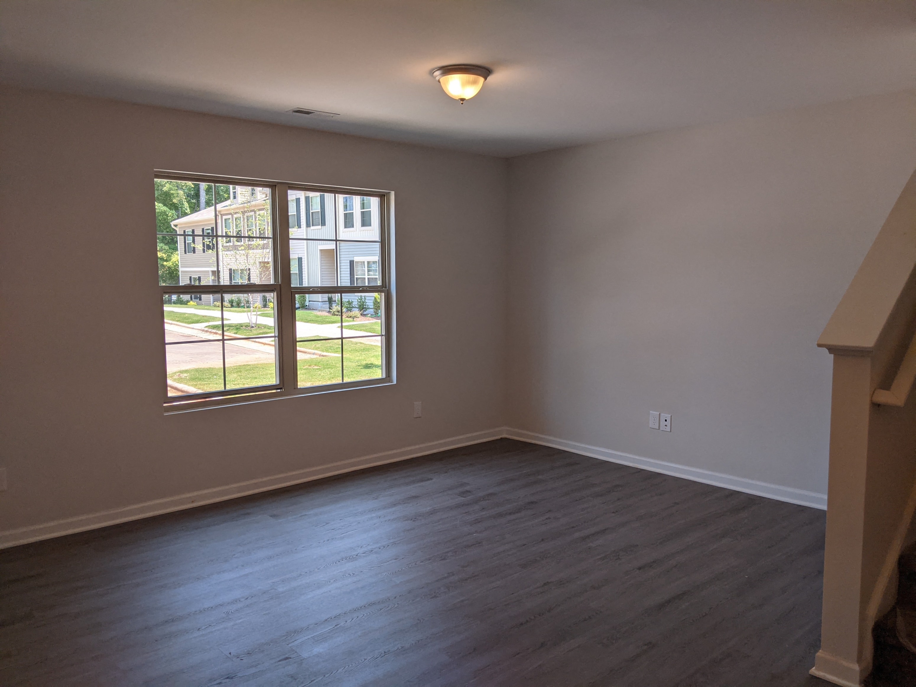 A room with a large window and wooden flooring.
