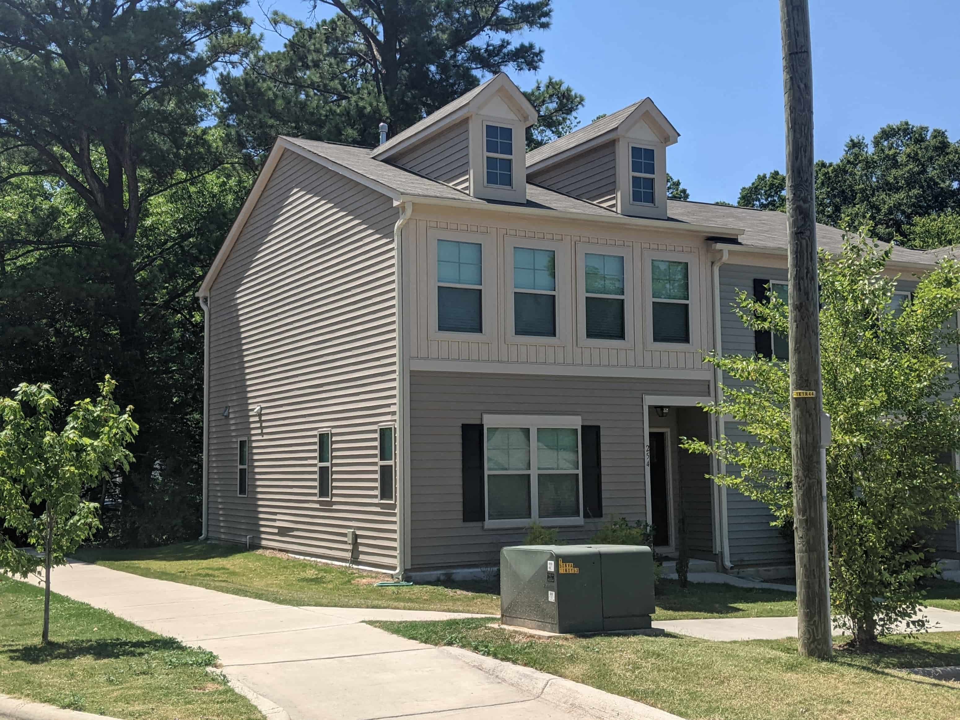 A house with a grey siding and a green utility box.