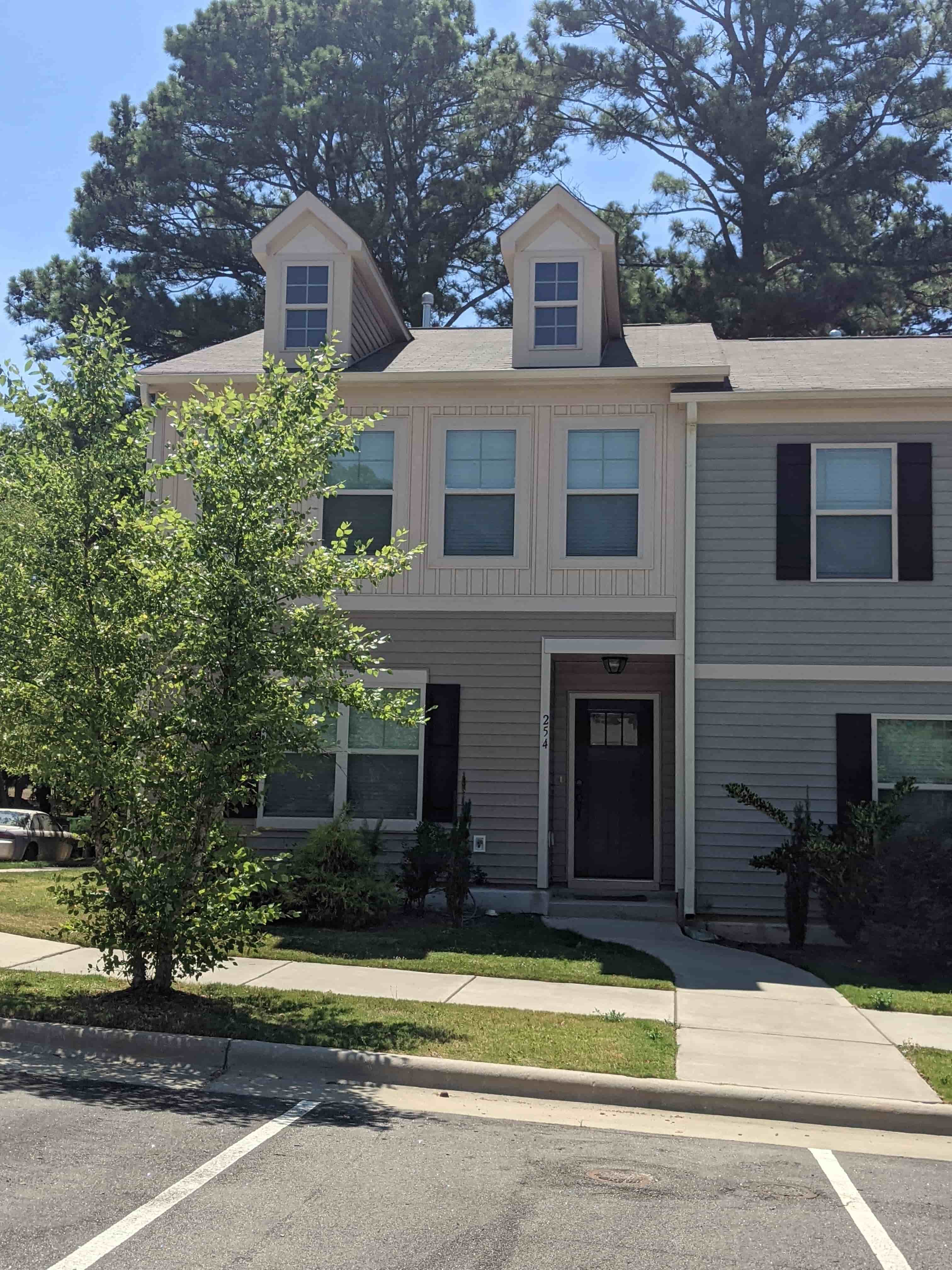 A two-story house with a grey facade and a black door.