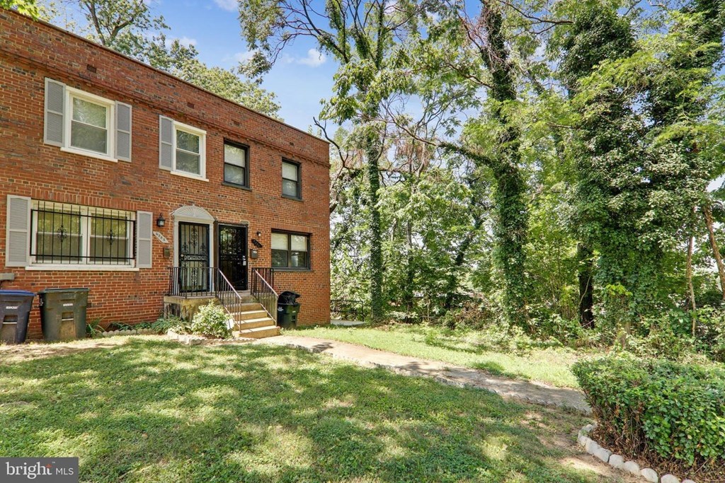 a red brick house with a green lawn and trees