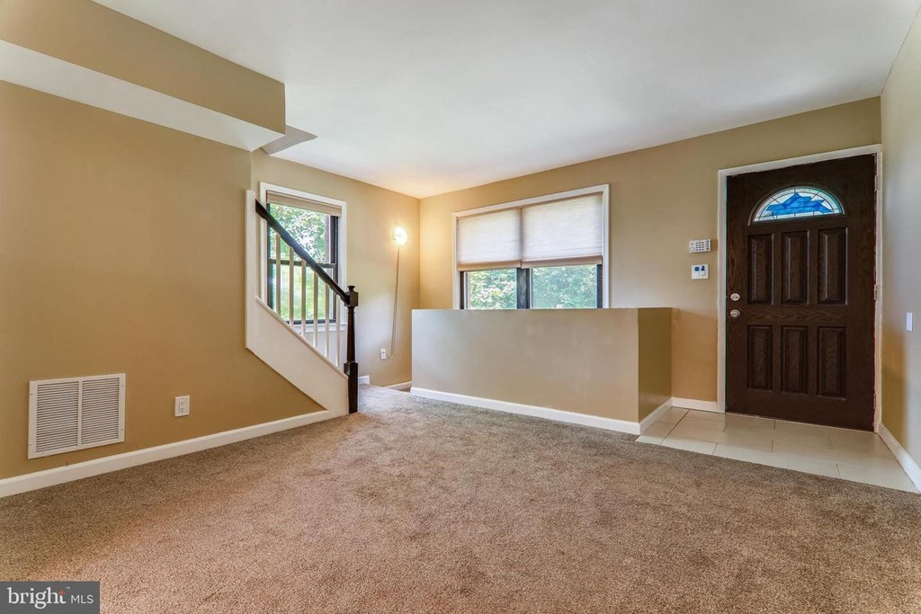 an empty living room with a wooden door and a window