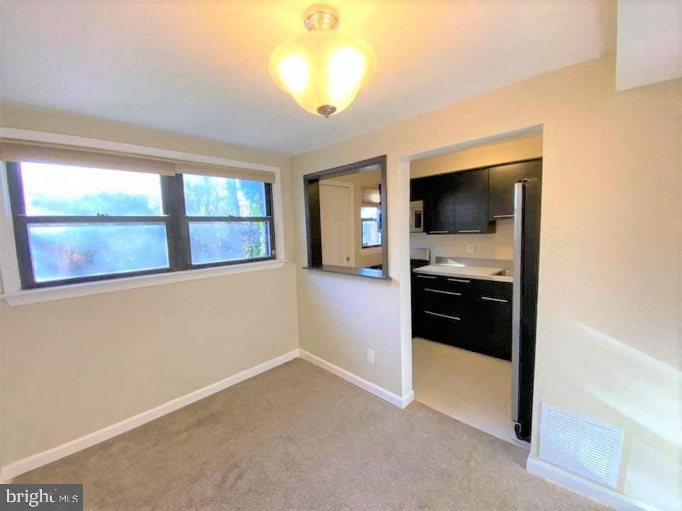 an empty living room with a window and a kitchen