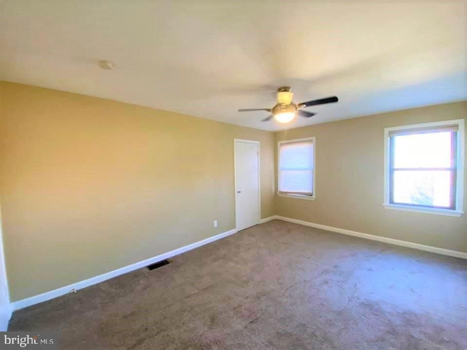 an empty living room with a ceiling fan and a window