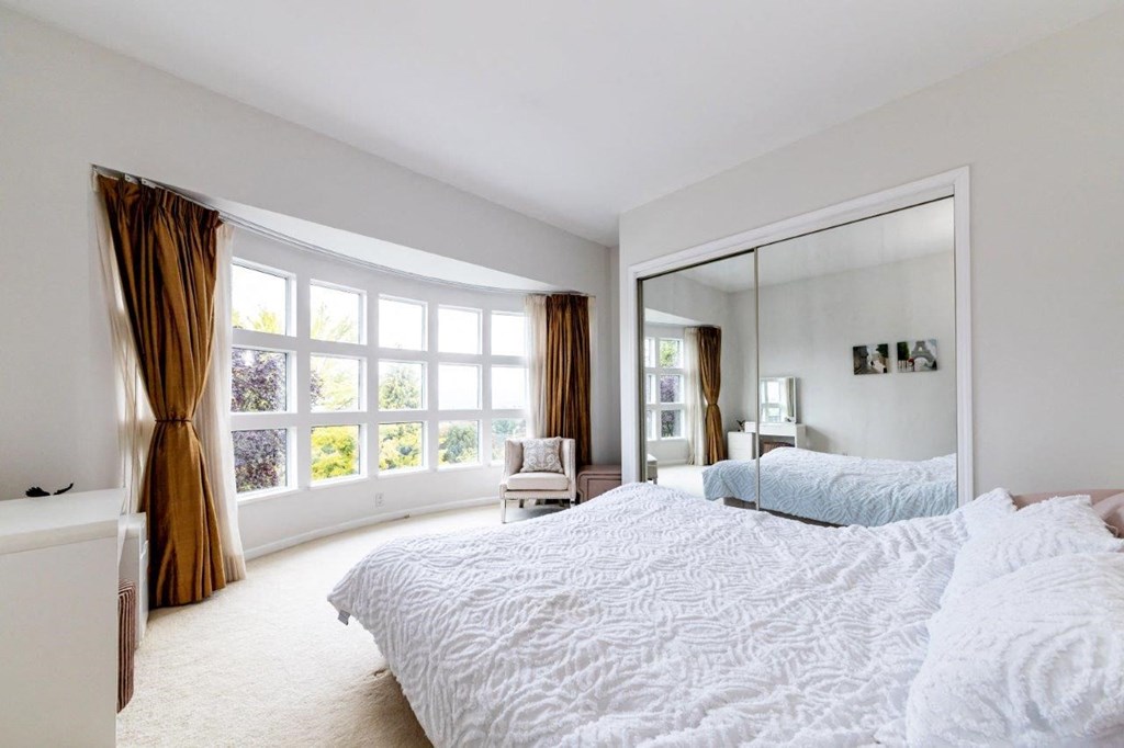 a large white bedroom with a large bed and a large mirror