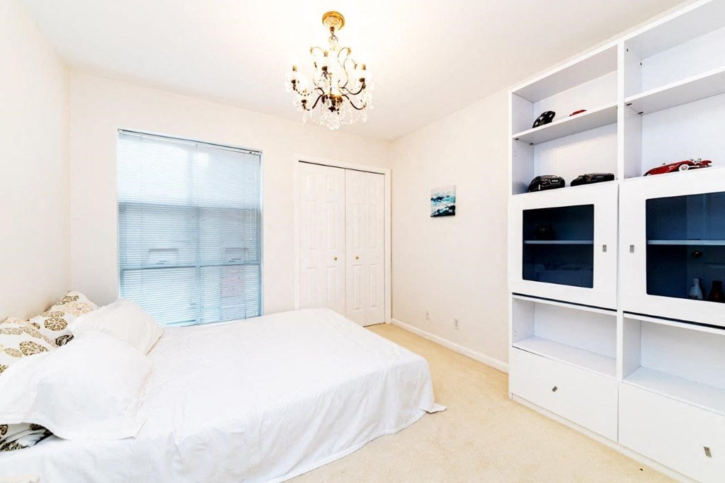 a white bedroom with a bed and a chandelier