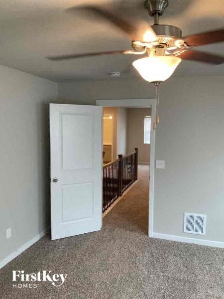 a bedroom with a ceiling fan and a door to a hallway