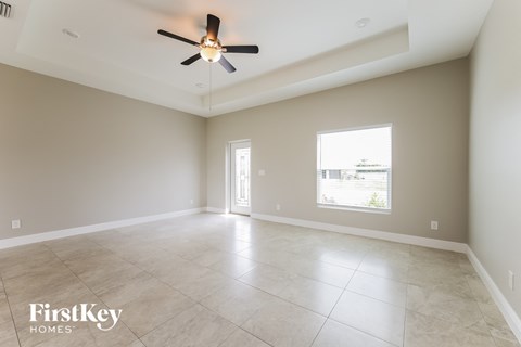 A spacious room with a ceiling fan and a large window.