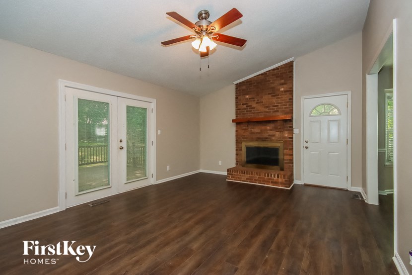 an empty living room with a fireplace and a ceiling fan