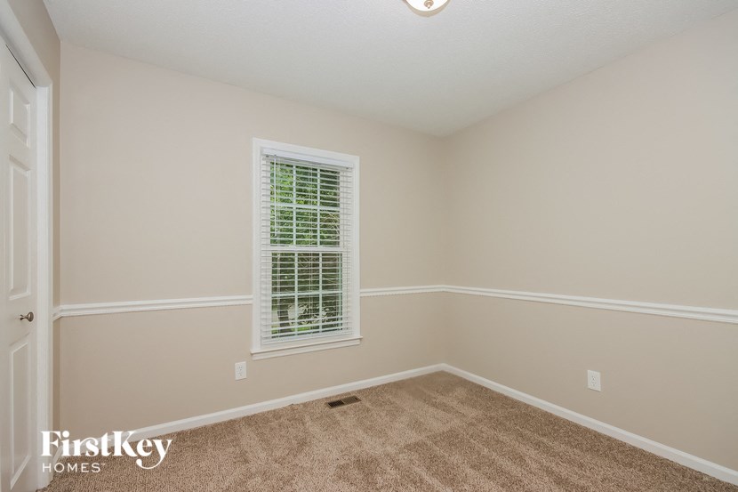 a bedroom with a window and a carpeted floor