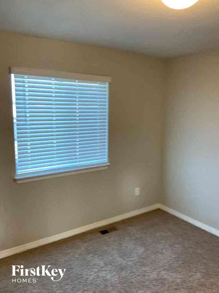 A room with a window covered in blinds and a carpet on the floor.