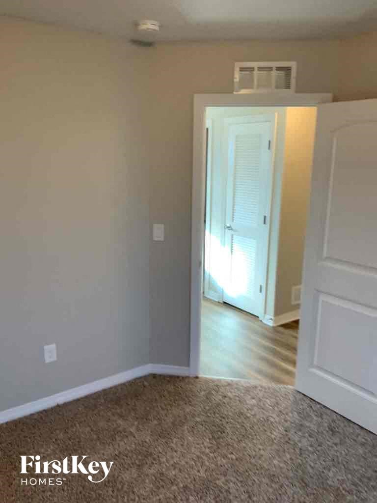 A room with a white door and a carpet on the floor.