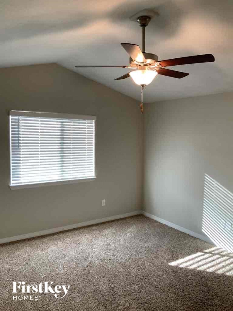 A room with a ceiling fan and a window with blinds.