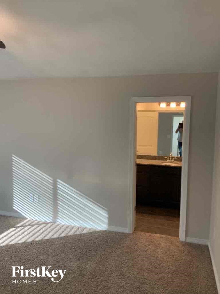 A carpeted room with a mirror and a window with blinds.