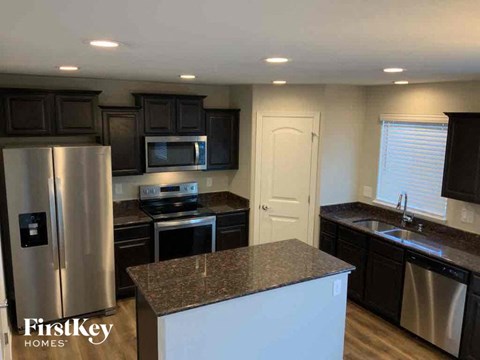 A kitchen with a refrigerator, microwave, oven, sink and cabinets.