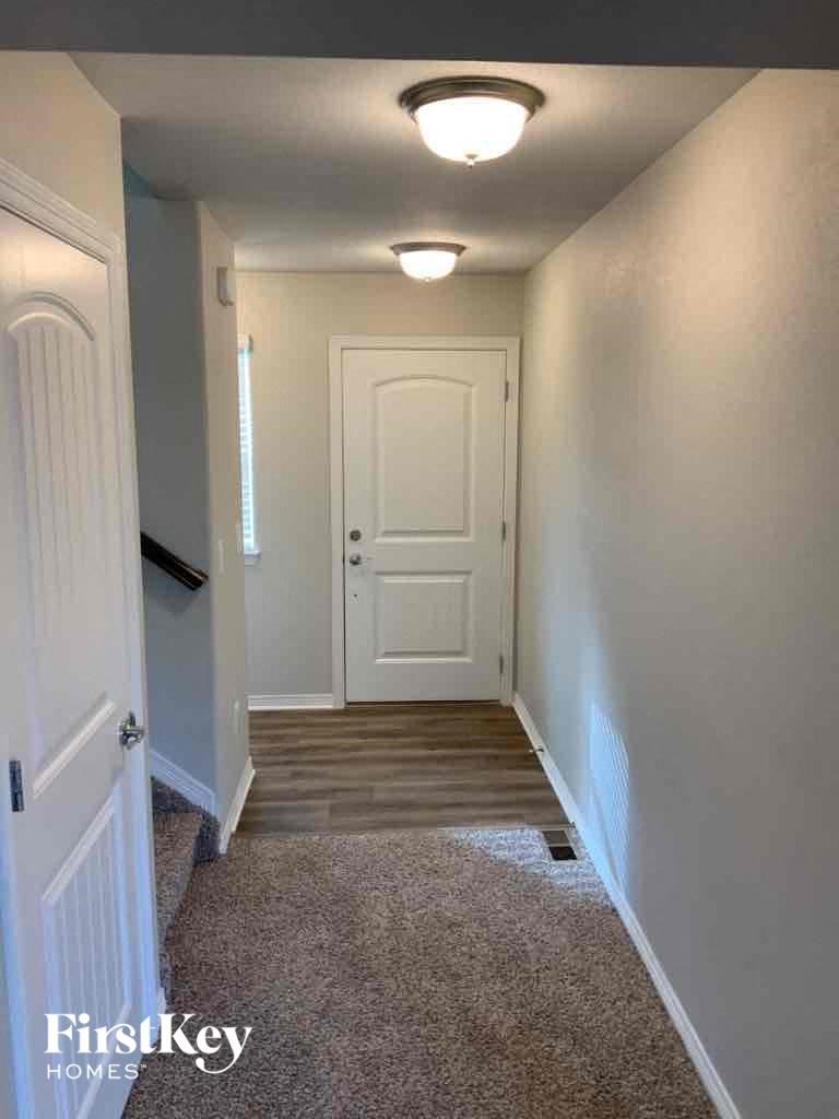 A hallway with a carpeted floor and white walls.