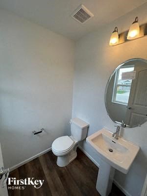 A bathroom with a toilet, sink, and mirror.