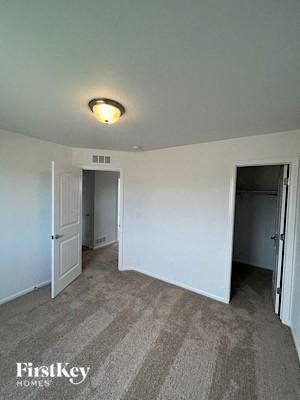 A room with carpeted floor and two doors.