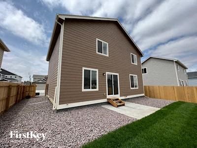 A house with a brown siding and a gravel driveway.