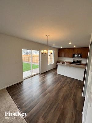 A spacious room with wooden flooring and a kitchen area in the background.