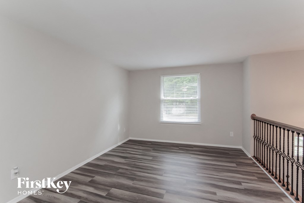 a room with a staircase and a window and wooden floors