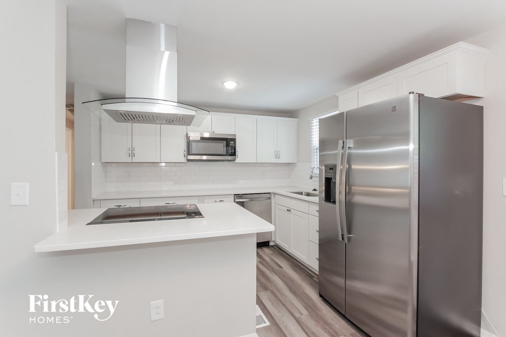 a white kitchen with stainless steel appliances and white counter tops