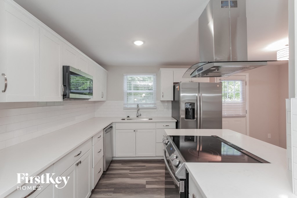 a white kitchen with stainless steel appliances and white counter tops