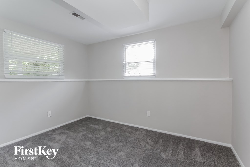 a bedroom with a carpeted floor and two windows
