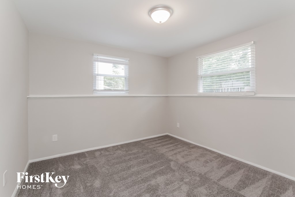 a bedroom with two windows and a carpeted floor