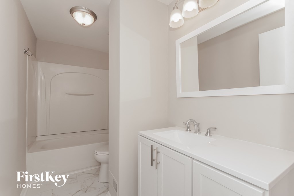 a white bathroom with a sink and a toilet and a mirror