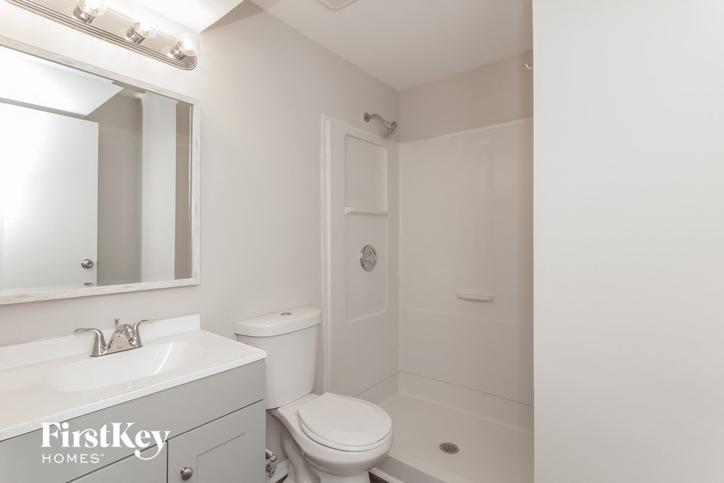 a white bathroom with a toilet and a sink and a mirror