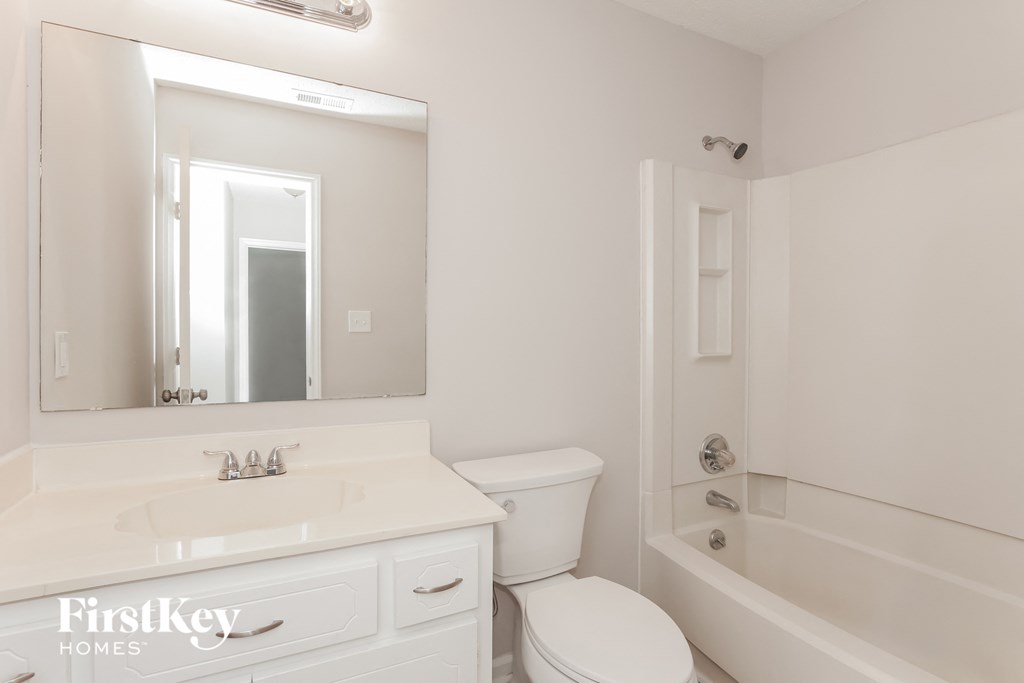 a white bathroom with a white sink and toilet and a bath tub