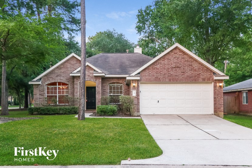 a small brick house with a driveway and grass