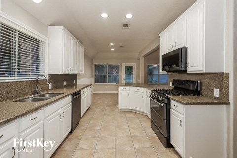 a large kitchen with white cabinets and black appliances