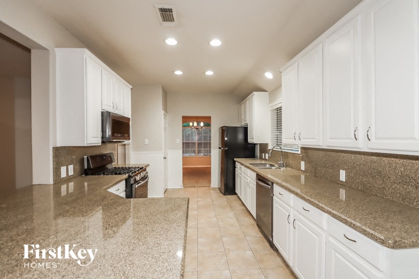 a large kitchen with white cabinets and granite counter tops