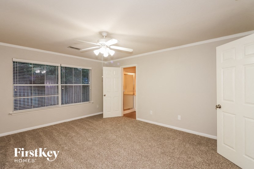 an empty bedroom with a ceiling fan and a window