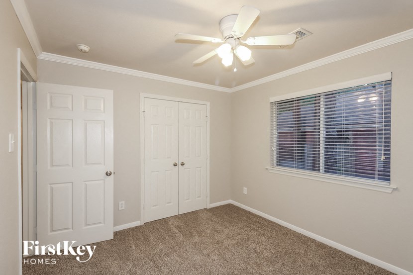 a bedroom with a ceiling fan and a window and a closet