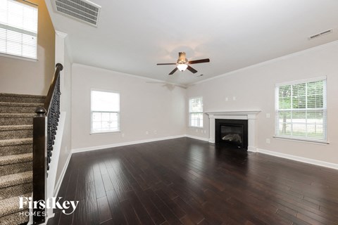 an empty living room with a ceiling fan and a fireplace
