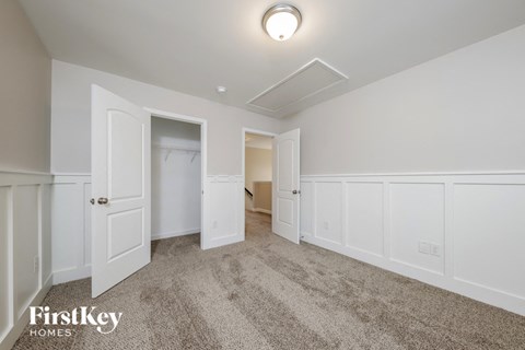 a bedroom with white walls and carpet and a door to a closet