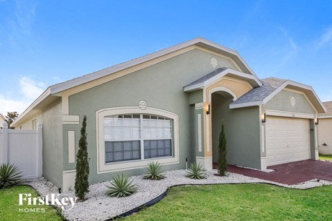 a green house with a lawn and a driveway