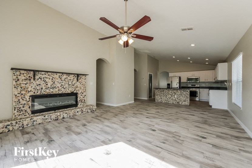 a spacious living room with a fireplace and a kitchen