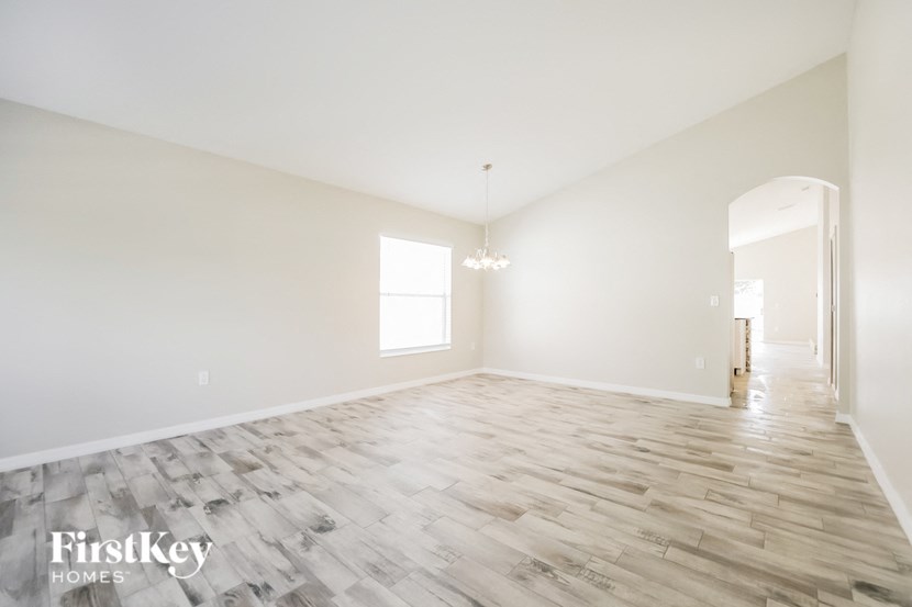 the living room and dining room of a new home with white walls and wood floors