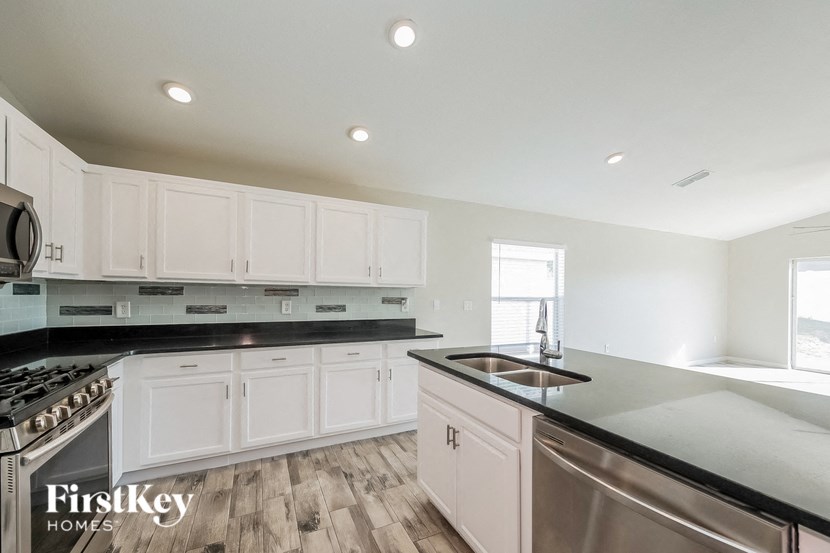 a kitchen with white cabinets and black counter tops and stainless steel appliances