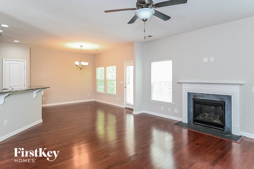 A spacious living room with a fireplace and a ceiling fan.