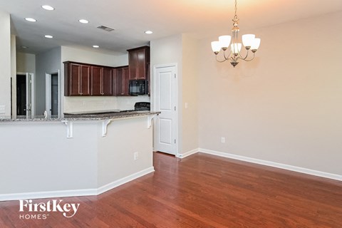 A well-lit kitchen with wooden floors and a chandelier.