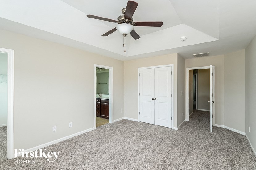 A spacious room with a ceiling fan and carpeted floor.