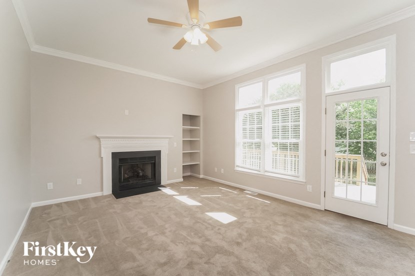an empty living room with a fireplace and a ceiling fan