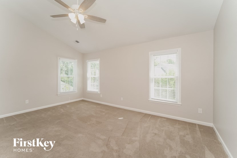 a empty room with a ceiling fan and two windows